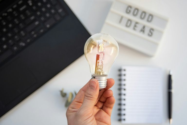 High view of a desk with a laptop, a notebook and a lightbulb
